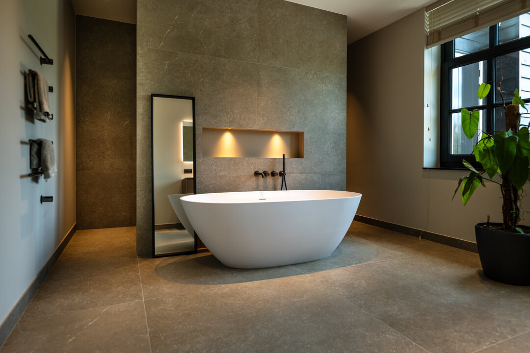 greiges Badezimmer mit freistehende Badewanne und Bronze Armaturen